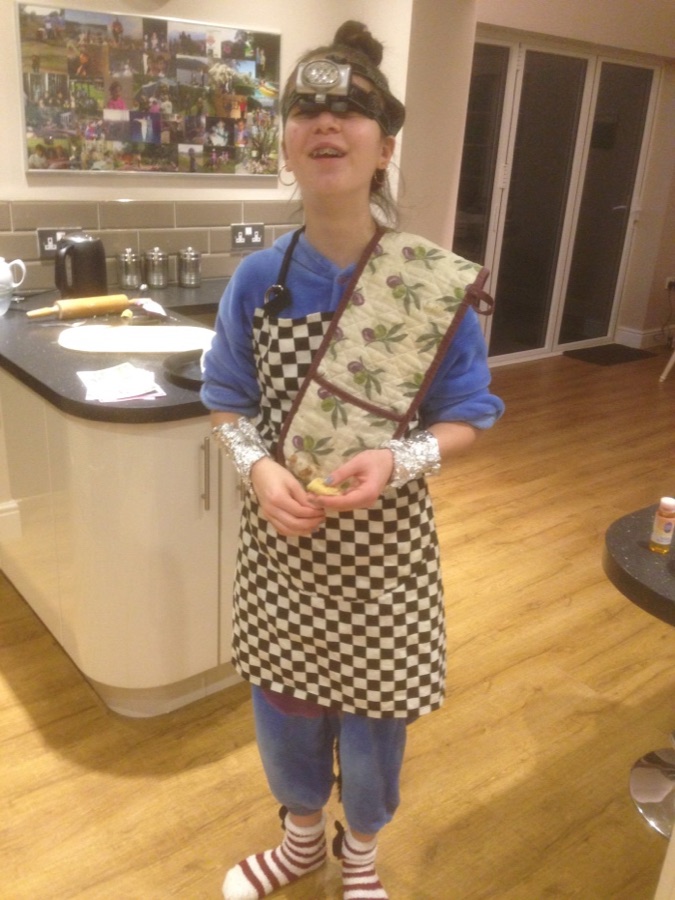 Bex Curran in a checkerboard apron and a head-torch, mid-recipe in her kitchen.